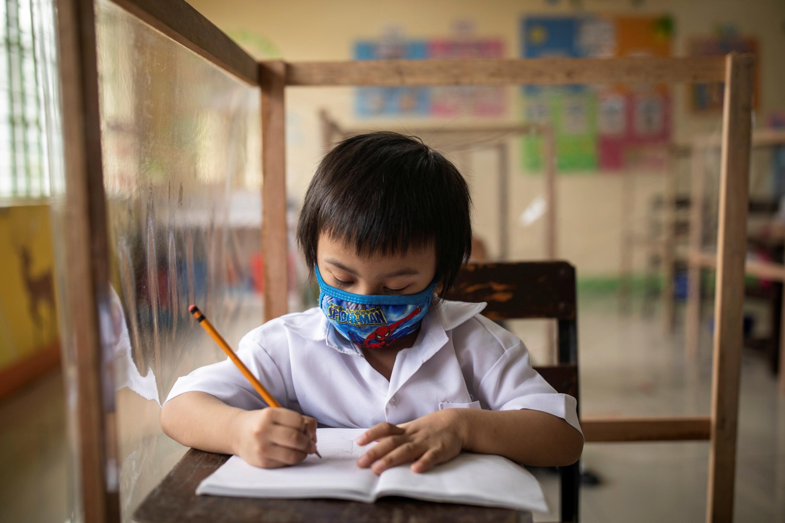 A student sits in a class with plastic barriers as schools reopen for the first time since the coronavirus pandemic began, in San Juan, Metro Manila, Philippines, on December 6, 2021. 