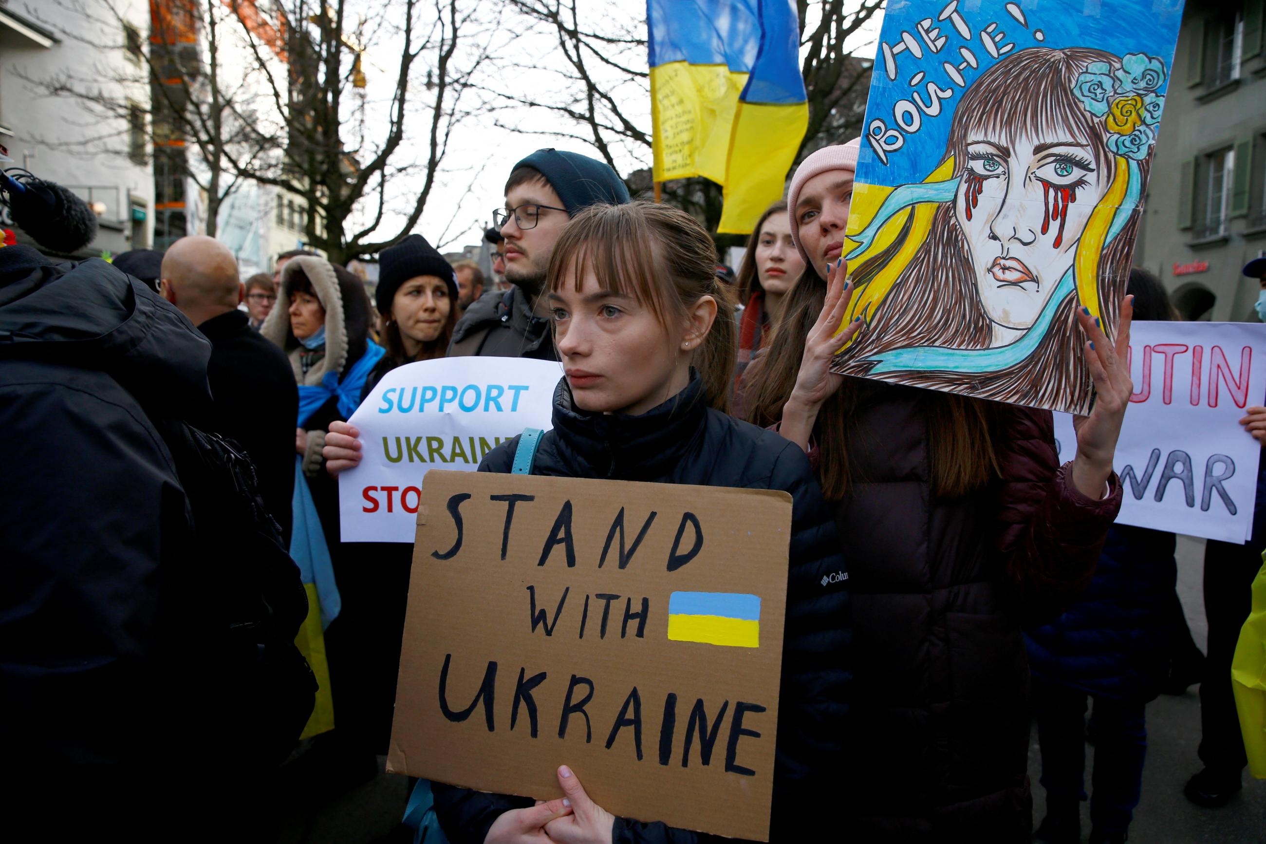 A woman displays a poster during a protest by Ukrainian people living in Switzerland, in Bern, Switzerland February 24, 2022. 