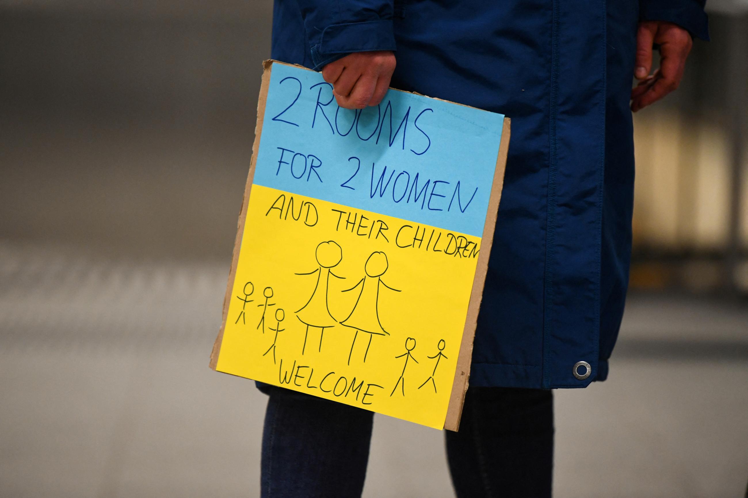 A woman holds a sign in the colors of the Ukraine flag, offering accommodation for refugees who arrive at Berlin Central Station, following Russia's invasion of Ukraine, in Berlin, Germany, March 3, 2022.