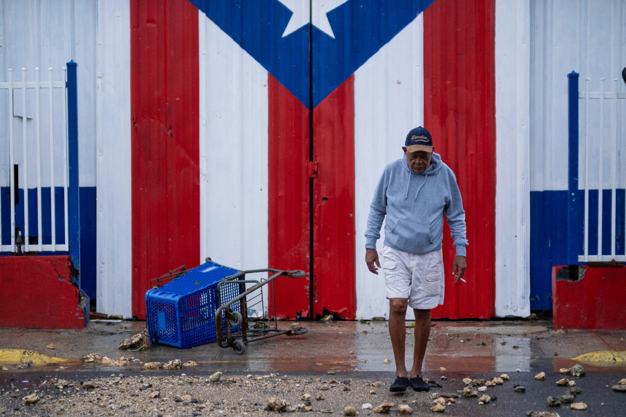 A large Puerto Rican flag painted on a door is seen behind a man, in the aftermath of Hurricane Fiona in Penuelas, Puerto Rico, on September 19, 2022. 