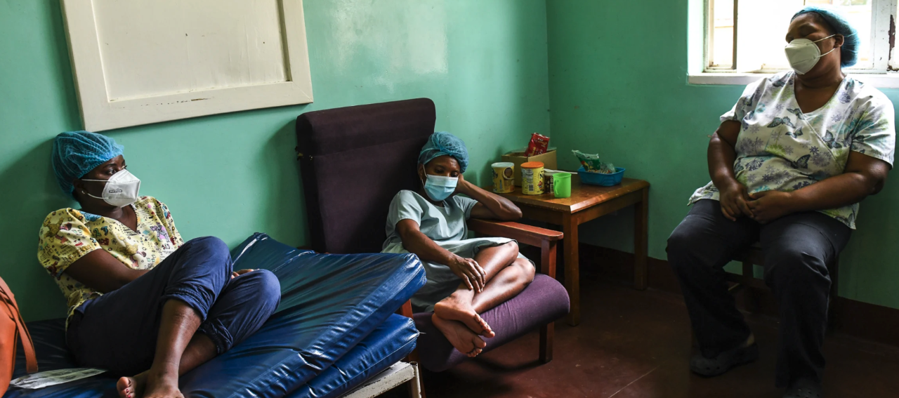 Three exhausted health workers rest on chairs and a couch during the January 2021 surge of COVID-19 at Queen Elizabeth Central Hospital in Blantyre, Malawi. 