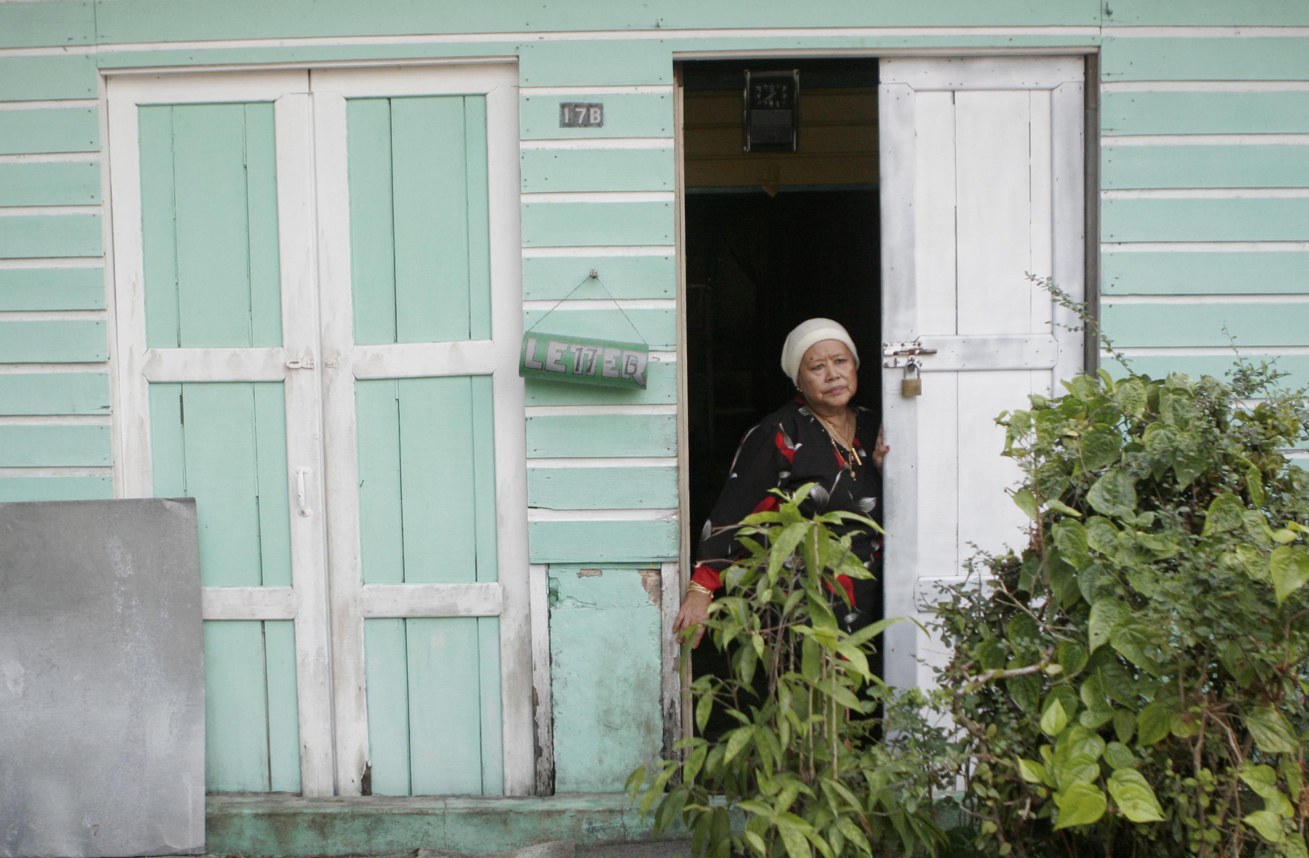 A woman looks out from her house 