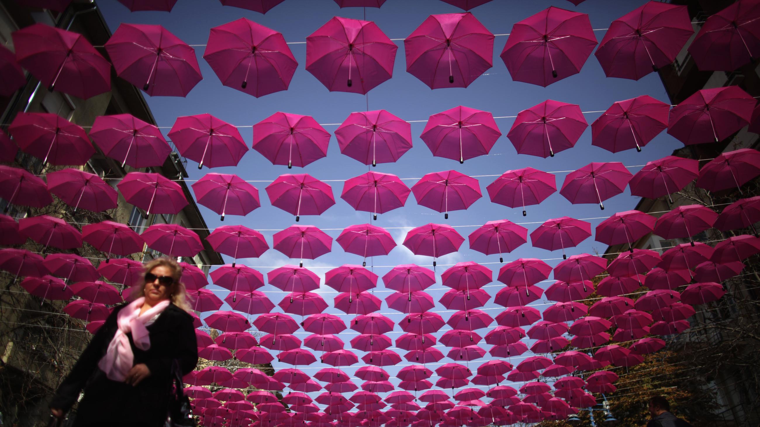 A woman walks under a canopy of pink umbrellas that are part of a campaign for breast cancer awareness, prevention and treatment.