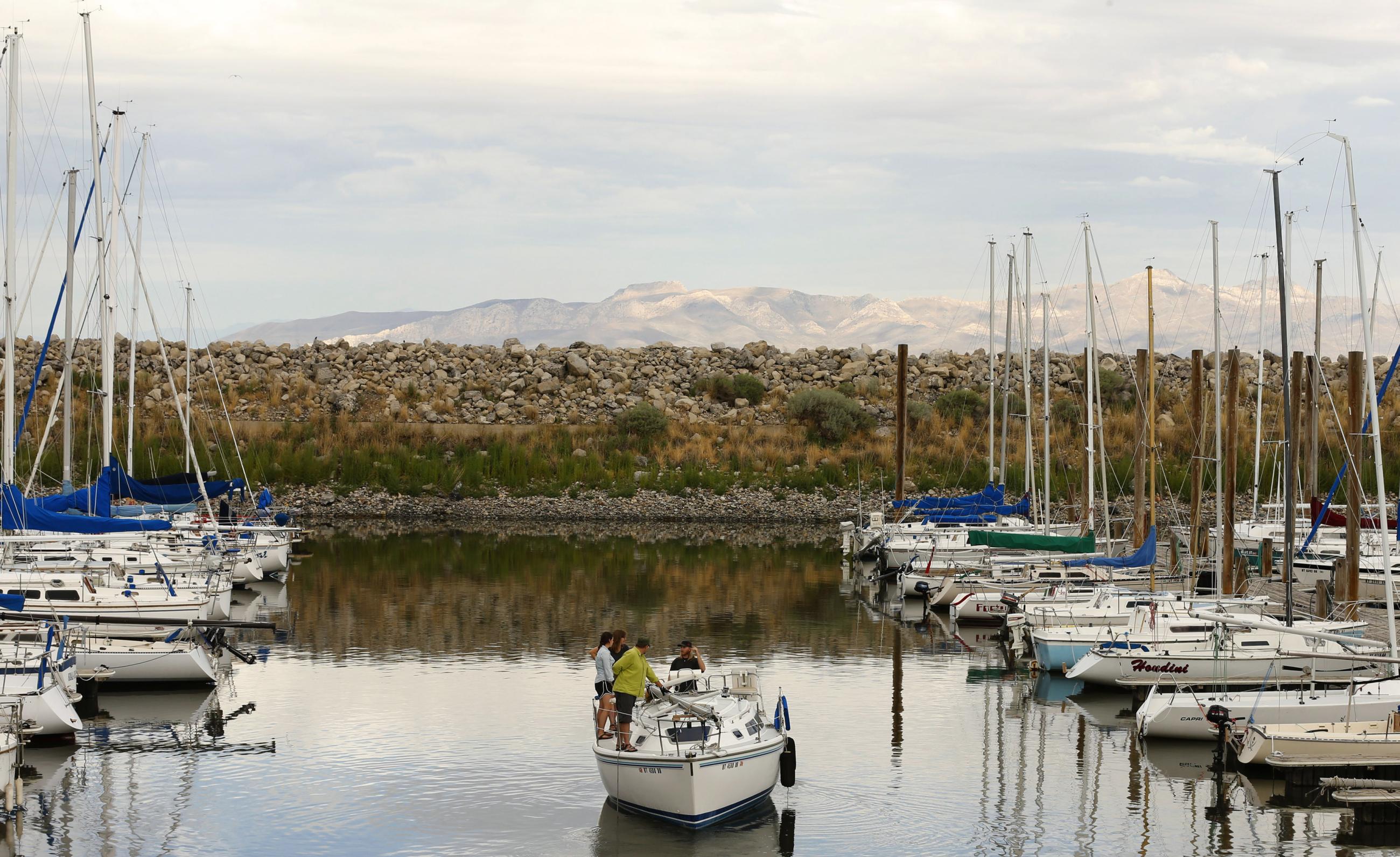 People move their boat into place to be lifted out of the water by a large crane at the Great Salt Lake Marina because of low water levels.
