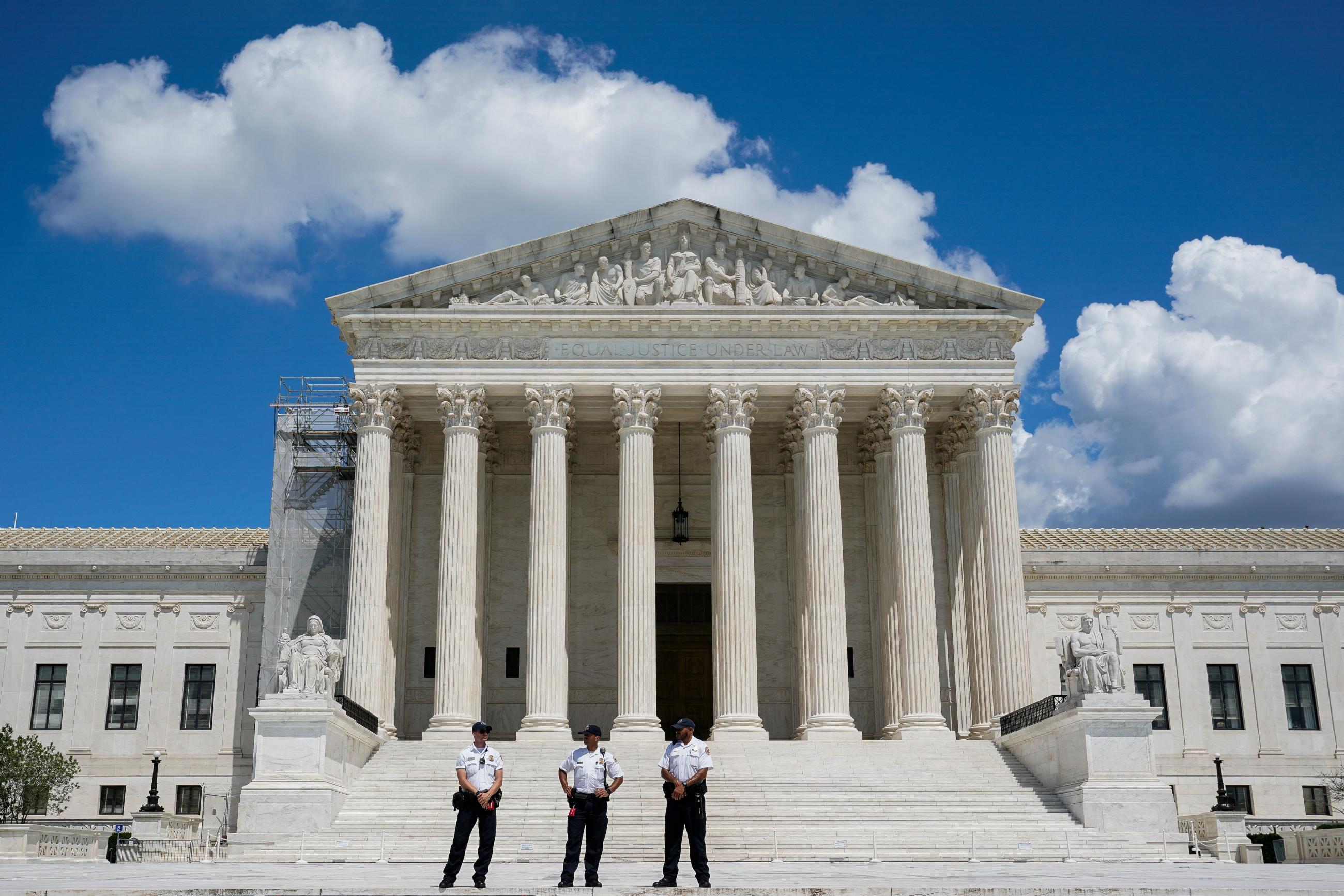 Law enforcement officers stand guard as abortion rights activists and counter protesters demonstrate outside the U.S. Supreme Court.