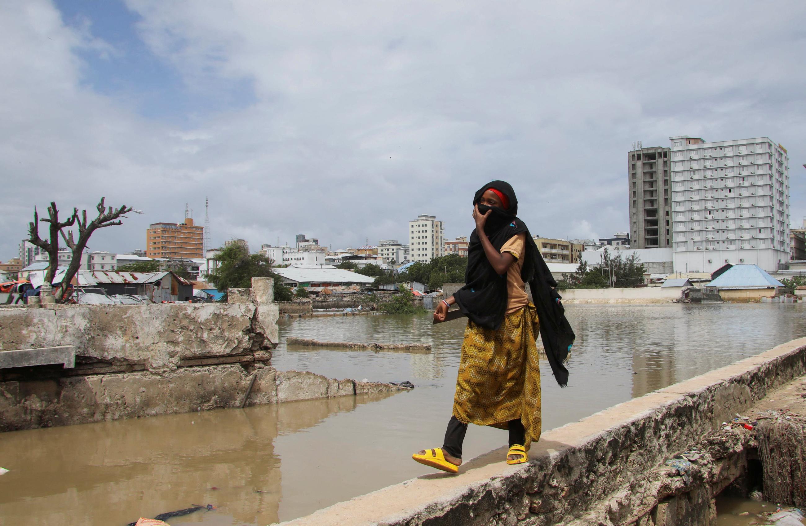 A woman walks next to flood waters.