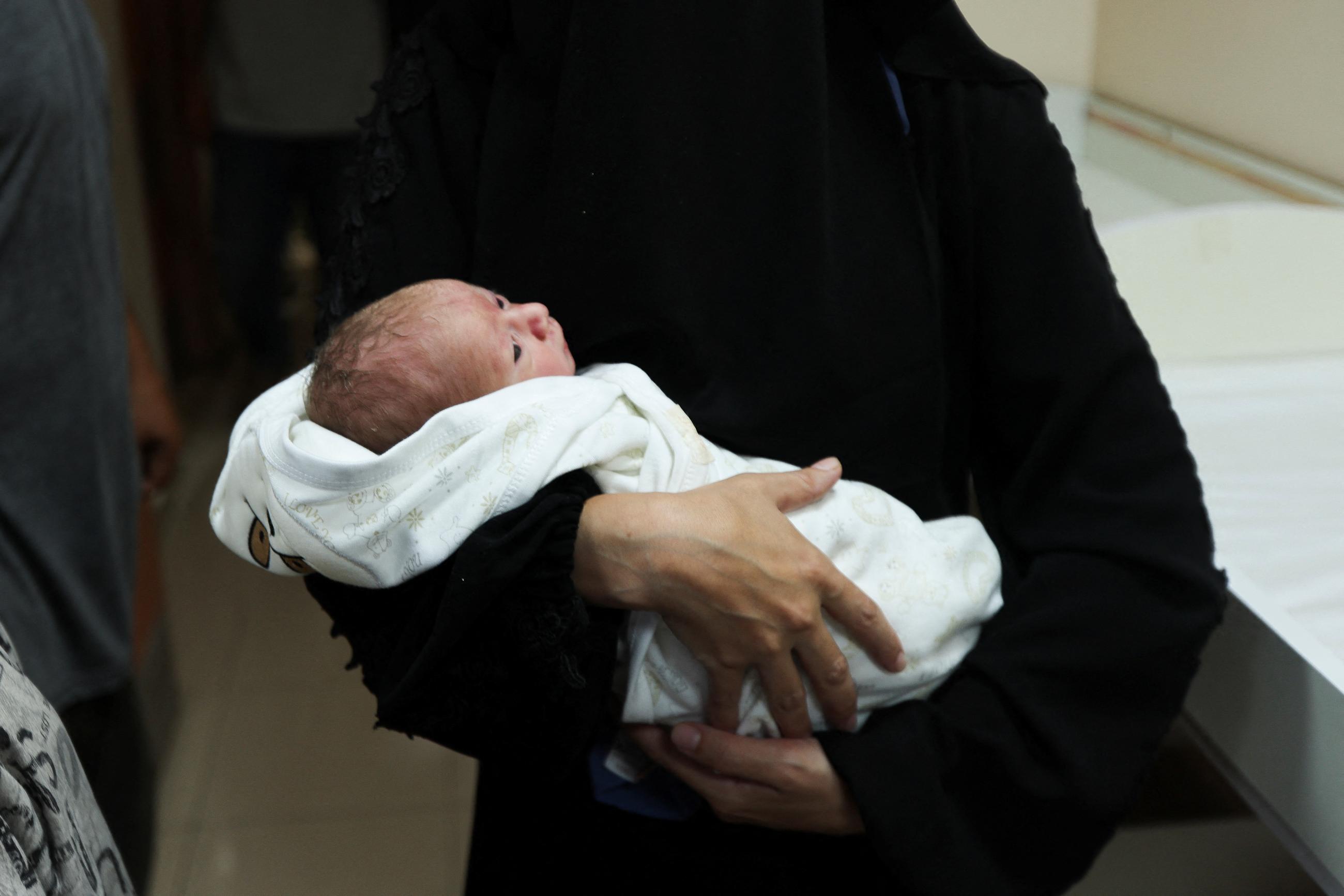 A baby is held in a person’s arms amid the ongoing Israel-Hamas conflict.