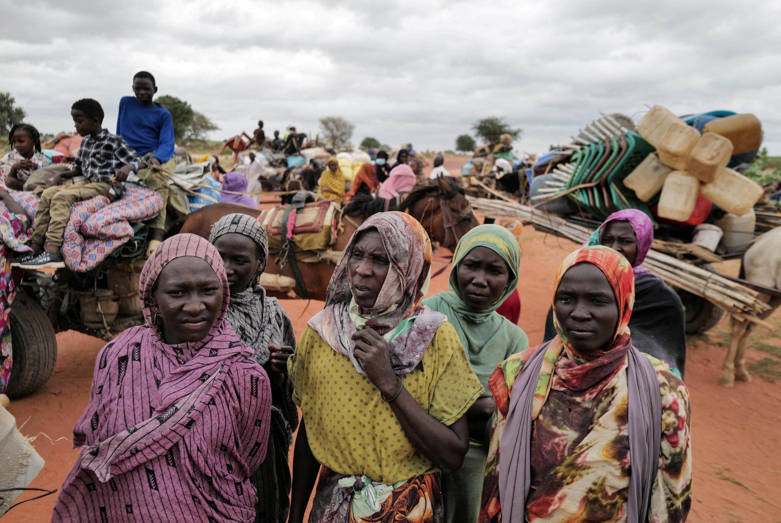 Sudanese women, who fled the conflict in Sudan, wait beside their belongings to be registered by UNHCR upon crossing the border between Sudan and Chad.