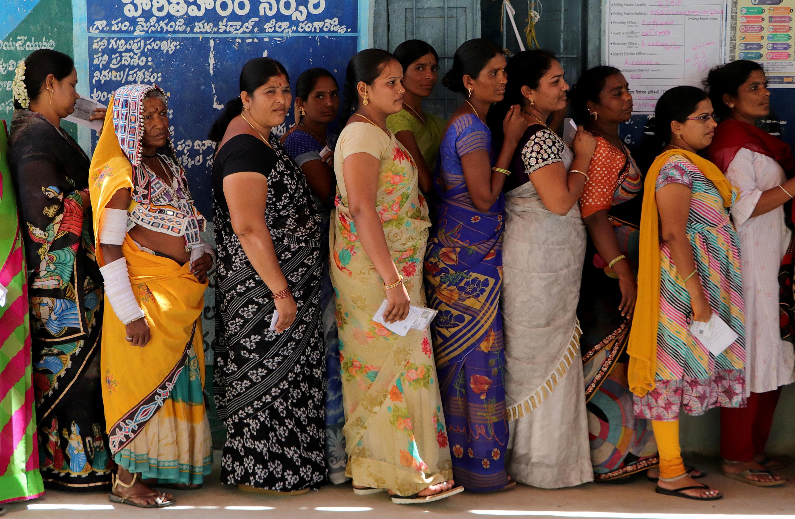 Women stand in a line to cast their votes at a polling station.