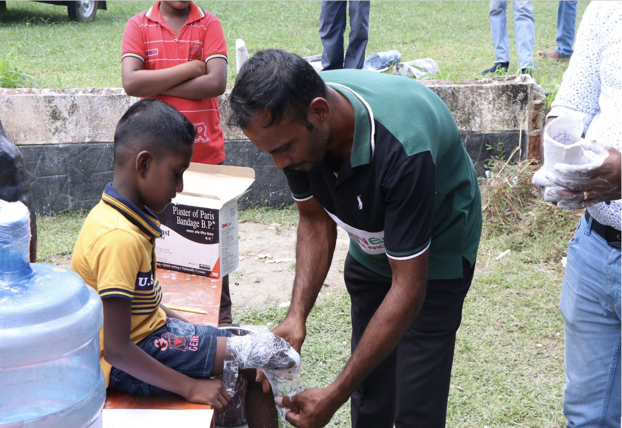 A man helps take a plaster cast of a young boy's limb.