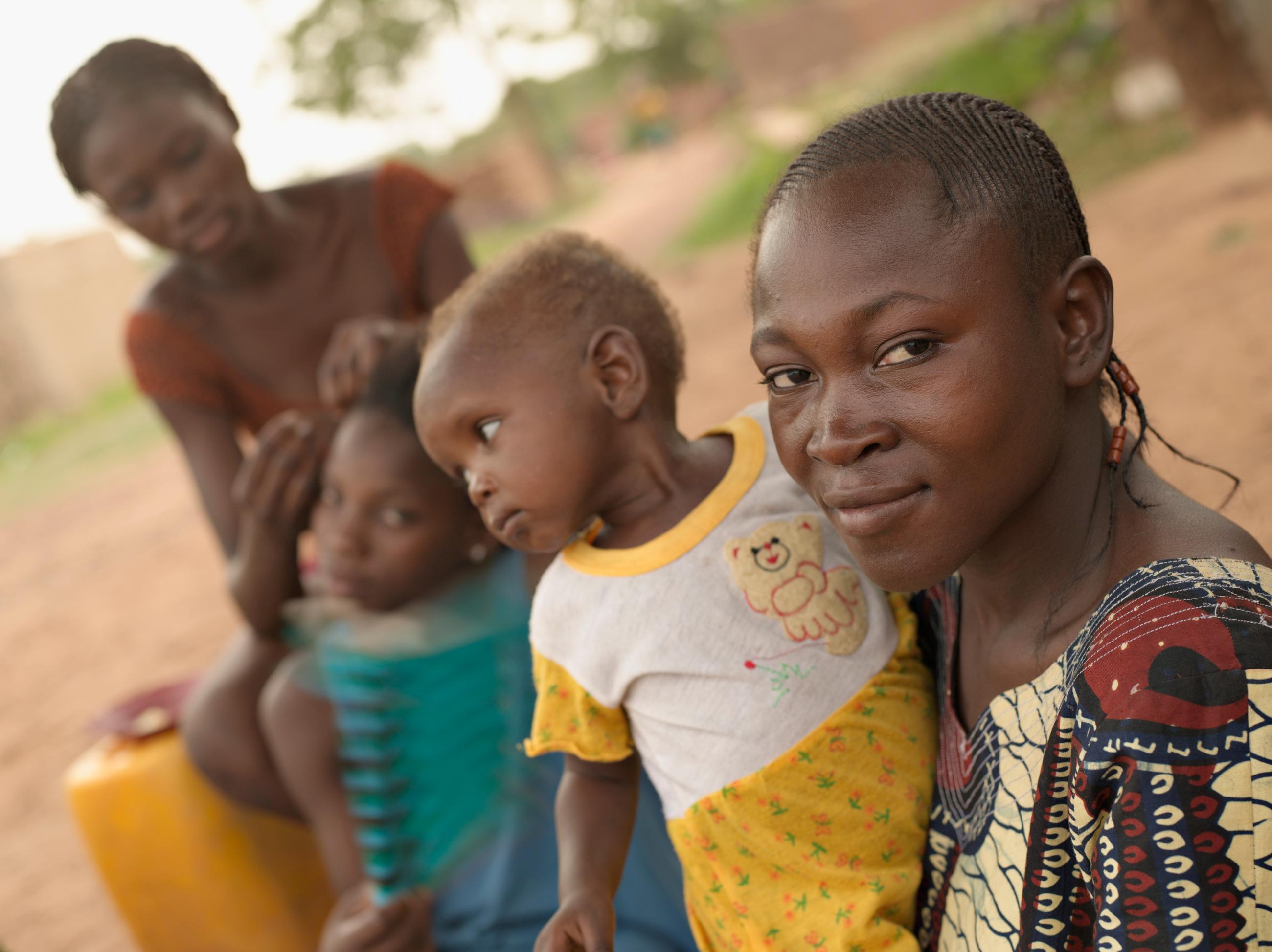 A woman and girls sit under a tree.