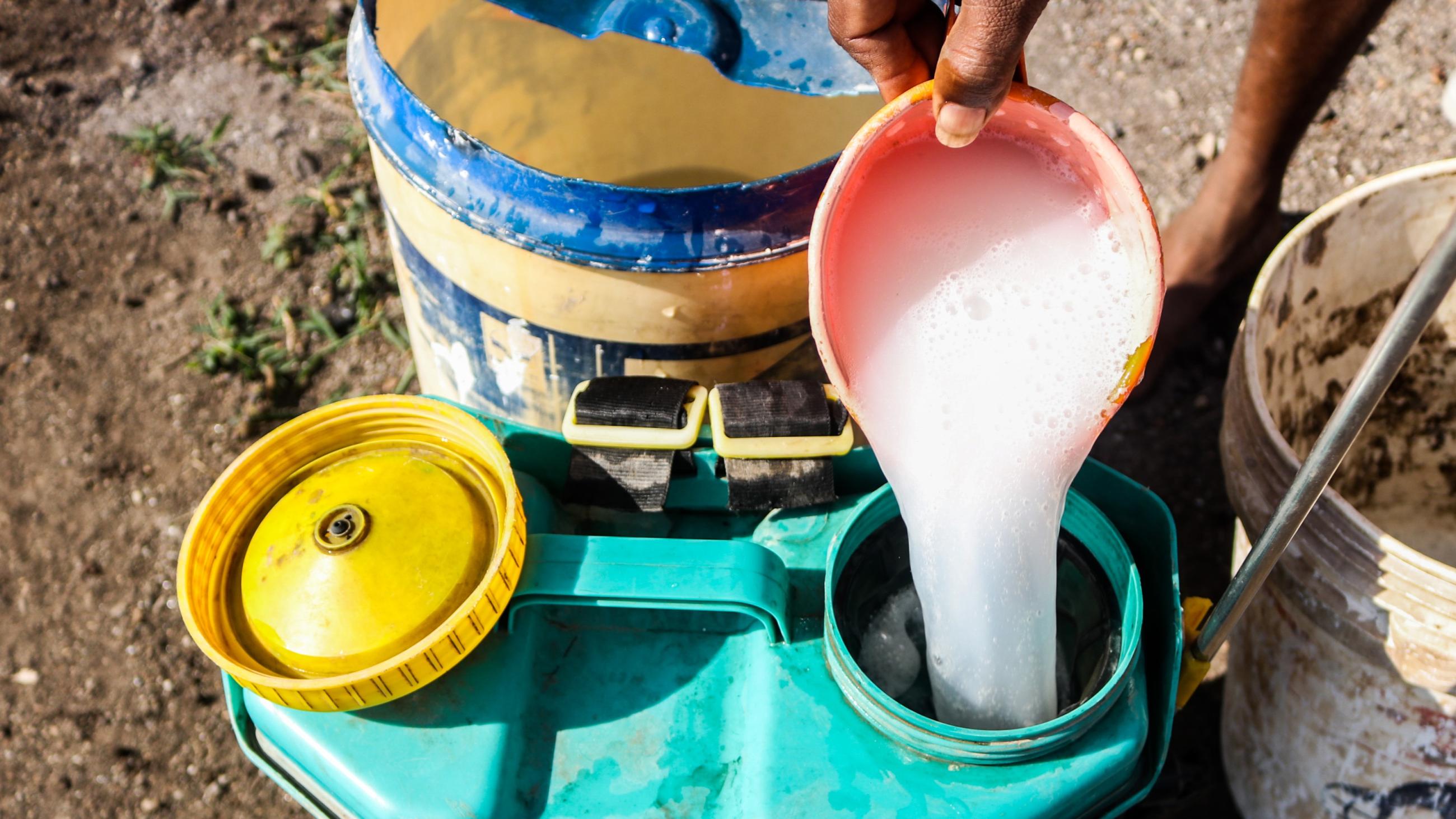 A farmer preparing a mixture of potent chemical pesticides to protect his vegetables. 