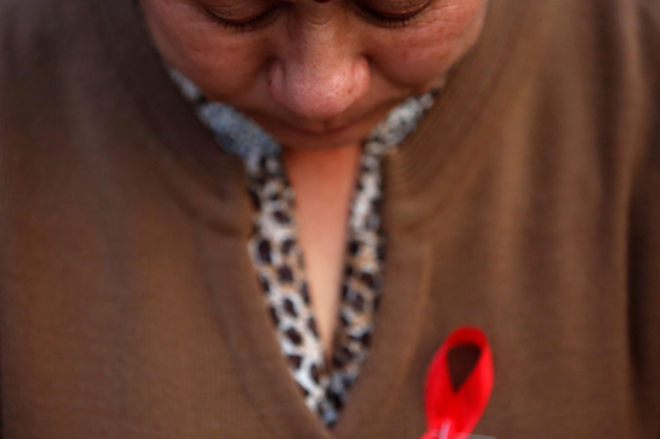 A participant with a red ribbon pin observes a minute of silence during a HIV/AIDS awareness campaign.
