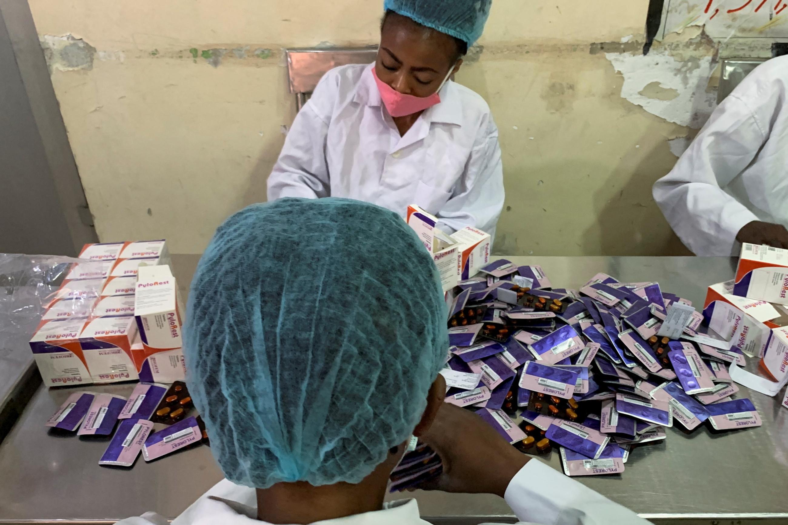 Workers at Biofem Industries processing facility stick authentication labels on drugs.