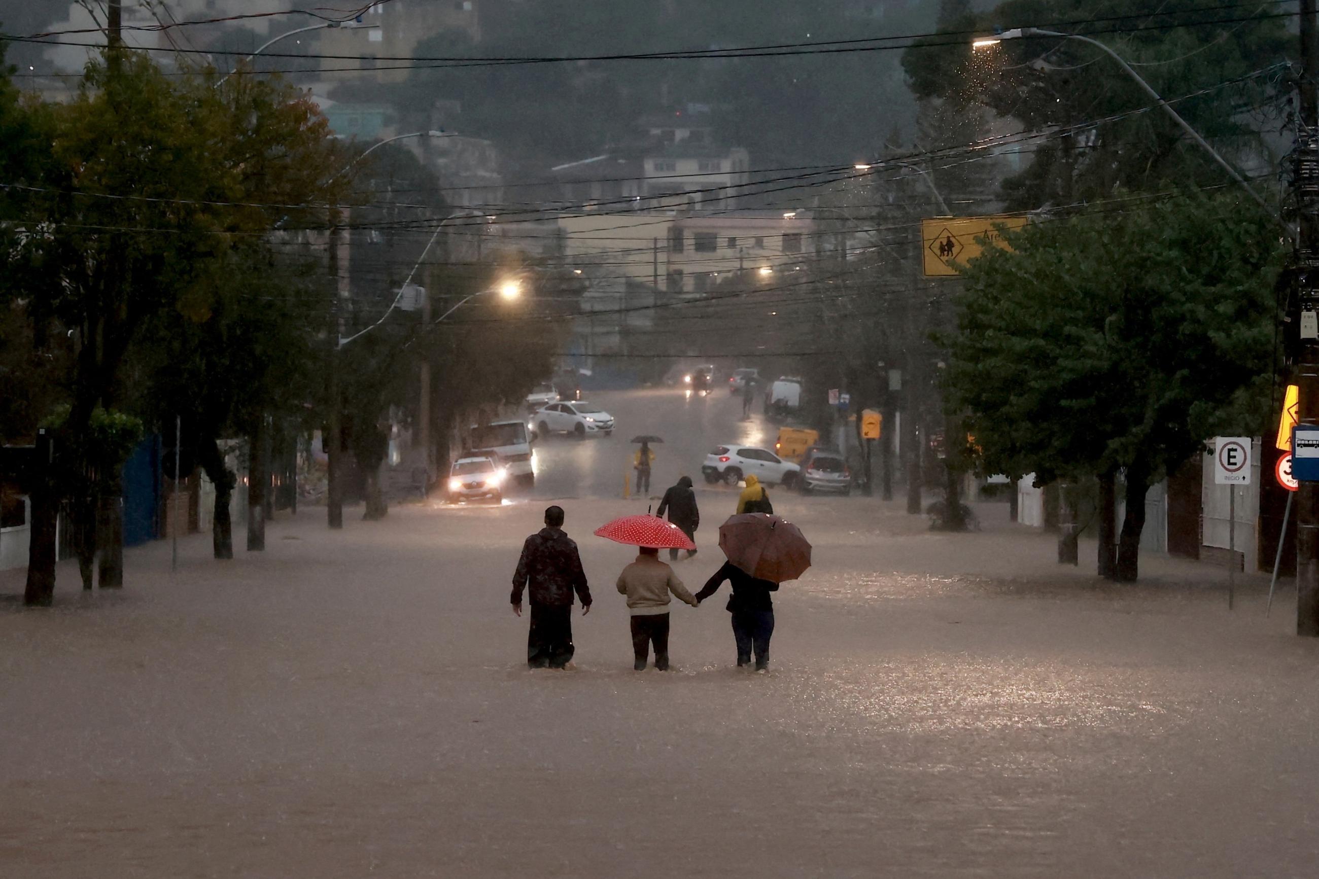 People walk in a flooded area in the Cavalhada neighborhood after heavy rains.