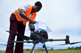 Joan Akullo, project coordinator for Medical Drones Project, loads a drone for delivery of medication, leaving from Bufumira sub-county to Kusu Village.