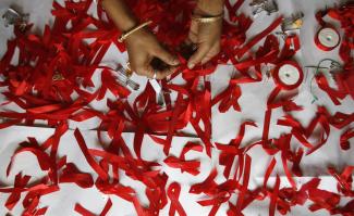 A volunteer suffering from HIV/AIDS makes AIDS symbols with red ribbons during a vaccination program.