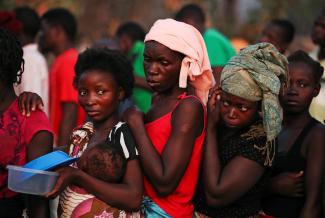 Women wait for food at a camp for people displaced in the aftermath of Cyclone Idai.