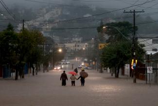 People walk in a flooded area in the Cavalhada neighborhood after heavy rains.