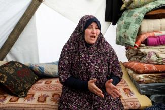 A displaced pregnant Palestinian woman speaks in a tent.