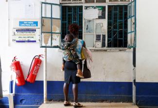 A woman carries her child as they stand at a payment counter.