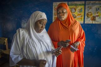 Jamila Usman, on right, in orange robe, is a health worker at the Tsafe hospital who does immunizations. The woman in white is the midwife, Aisha Abubsakar. Both work in the Maternity center at Tsafe General Hospital in Tsafe, Nigeria, where immunizations, family planning, pre-and post natal care as well as birthing are managed by midwives.