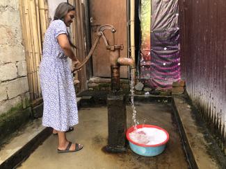 Sita Ghatani preparing to take a bath by pumping water, clearing foam, and then taking a bath from that water.