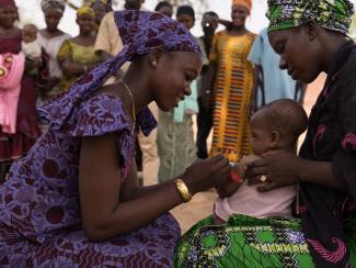 A community health worker evaluates a baby for malnutrition.