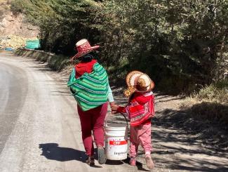 A mother and her daughter carry grain to their home in rural Cusco, Peru on July 21, 2022.