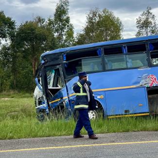 A man walks away from a bus that was involved in a disastrous head-on collision with a tractor trailer, in Macheke, Zimbabwe, in January 2024. 